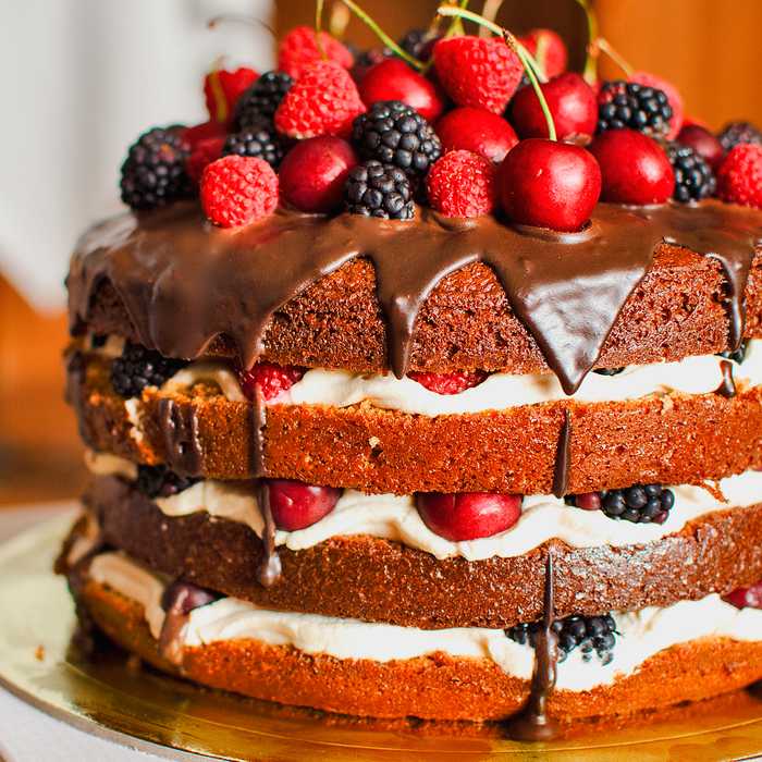 Шоколадный бисквитный торт, украшенный ягодами сверху и в начинке